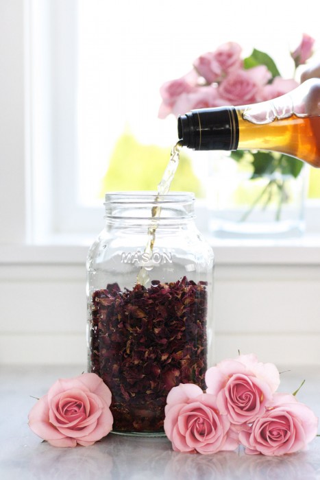 Pouring vinegar into jar full of dried rose petals