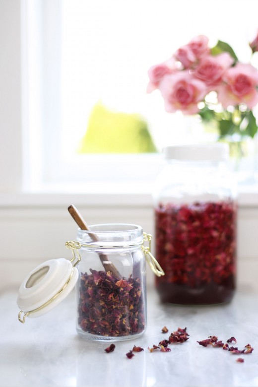 Small pretty jar filled with dried rose petals with jar of rose petal vinegar