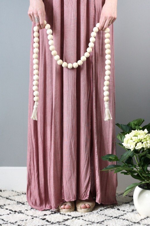 Woman in pink dress holding DIY wood bead garland