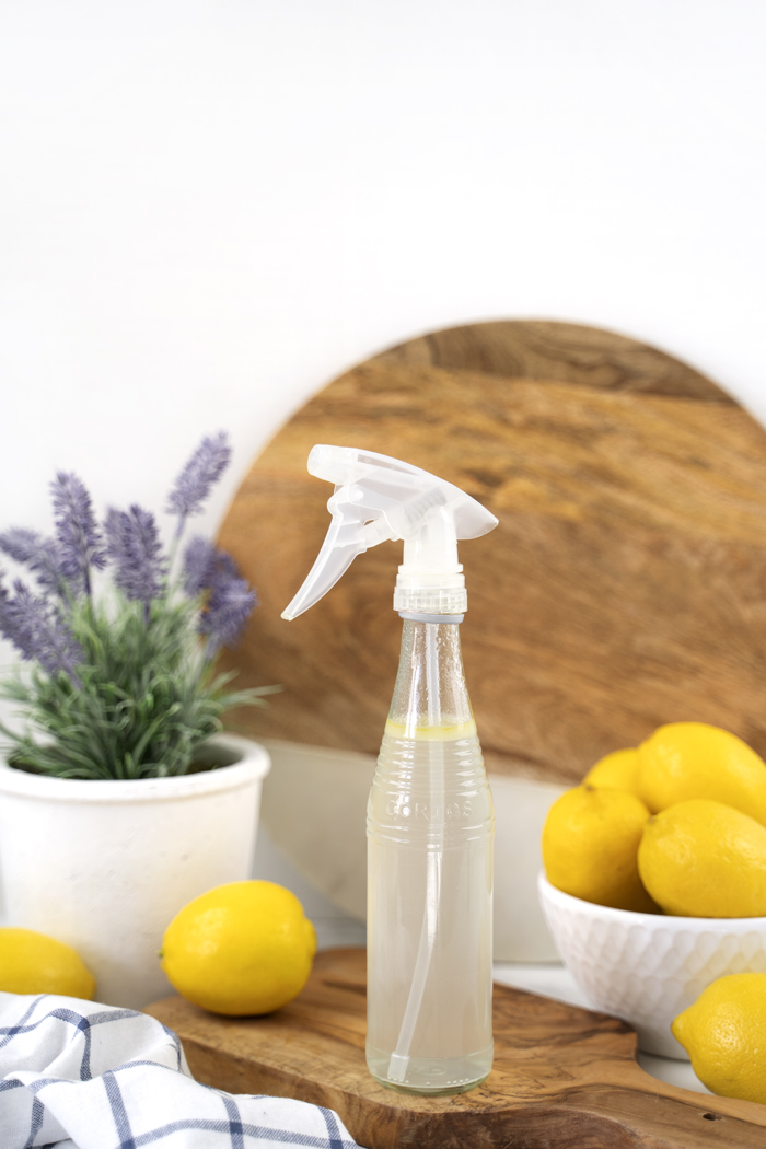 Bottle of DIY glass cleaner with bowl of lemons