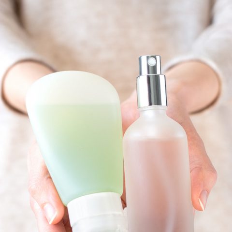 Hands holding bottles of homemade hand sanitizer