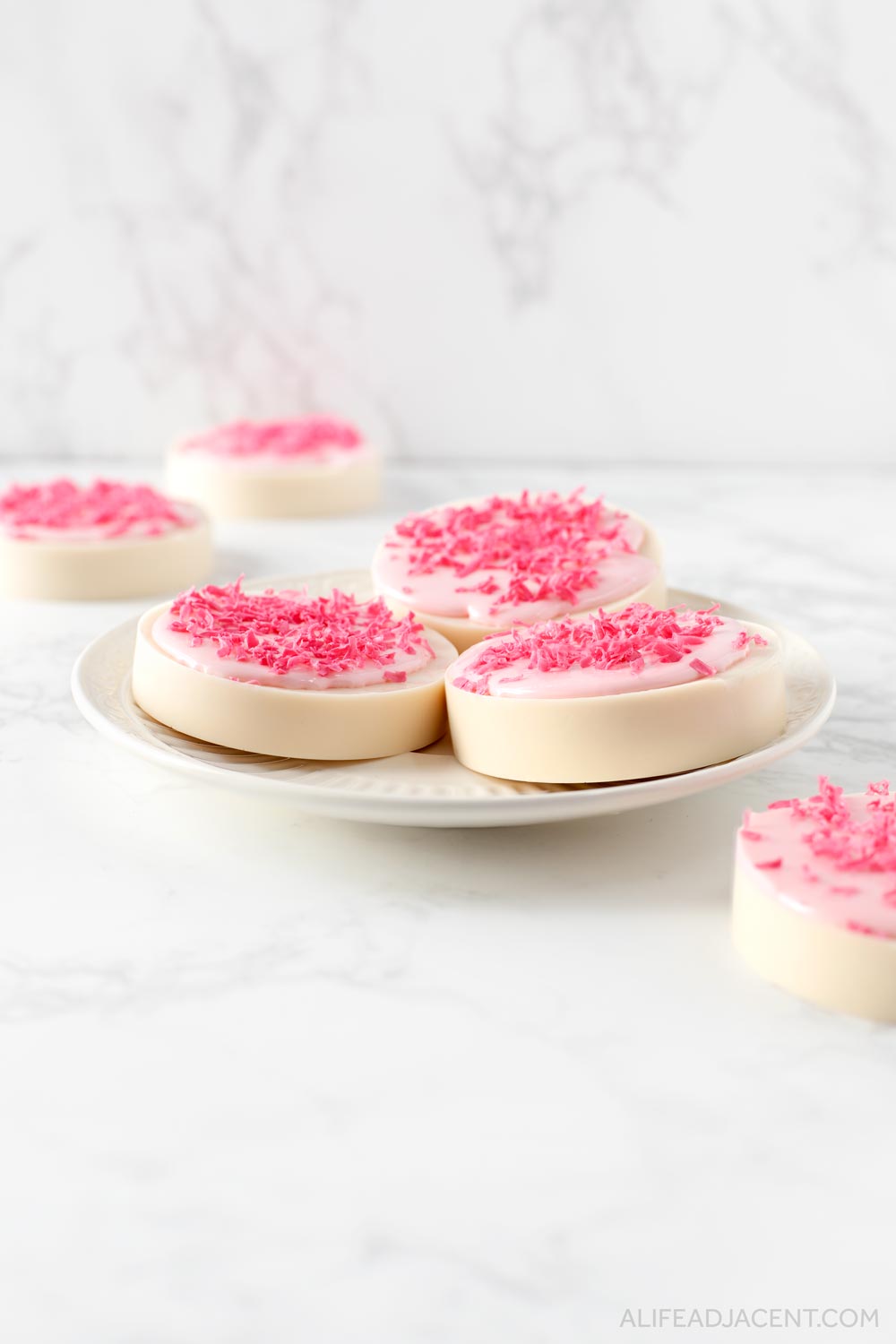 Sugar cookie soaps made with melt and pour soap are arranged on a plate