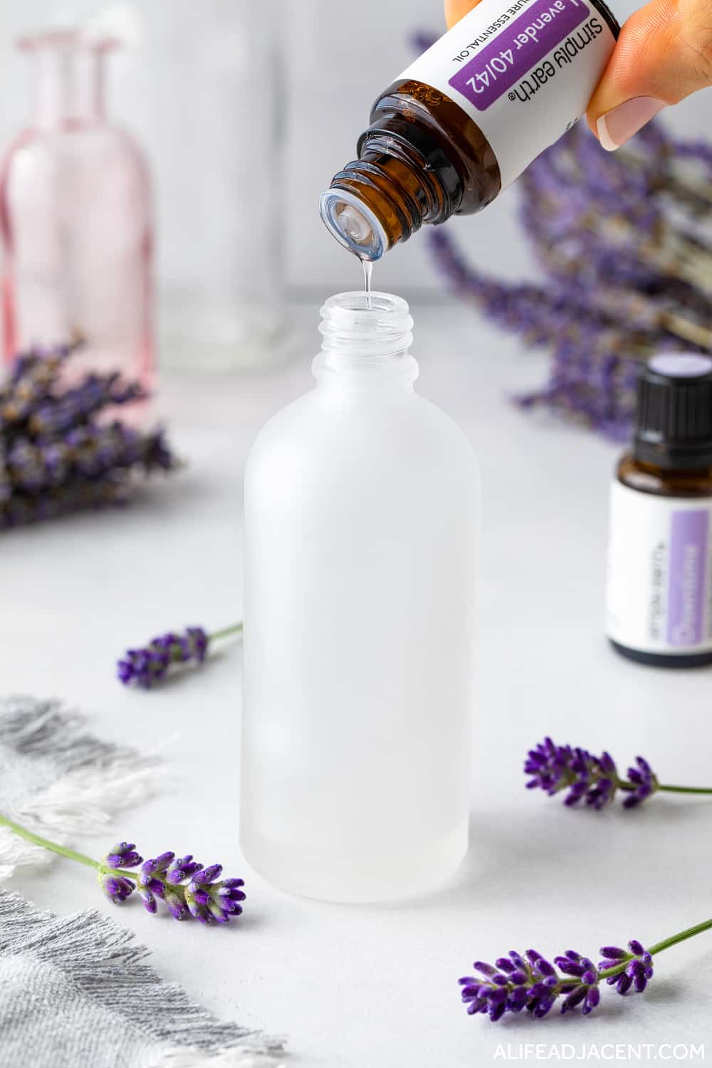 Making lavender spray for sleep – adding lavender essential oil to pillow spray bottle.