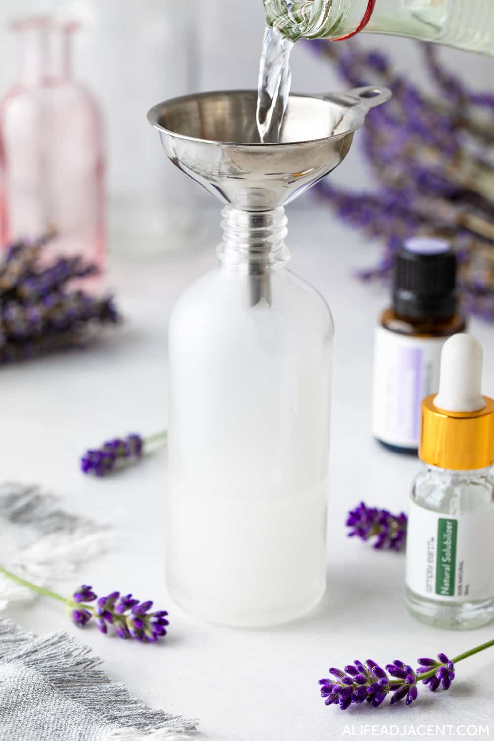 Pouring vodka into spray bottle to make pillow spray with essential oils