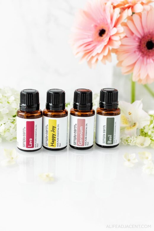 4 bottles of Simply Earth essential oils: Lava blend, Happy Joy blend, Geranium and Basil.