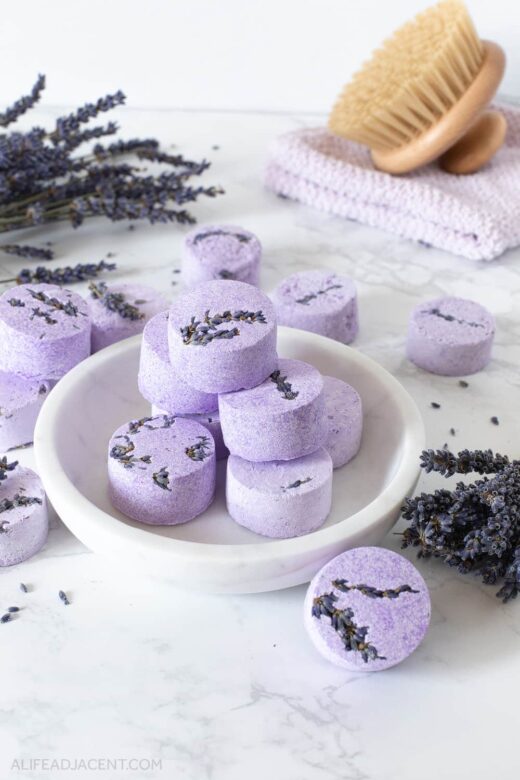 Lavender aromatherapy shower steamers on white marble plate.