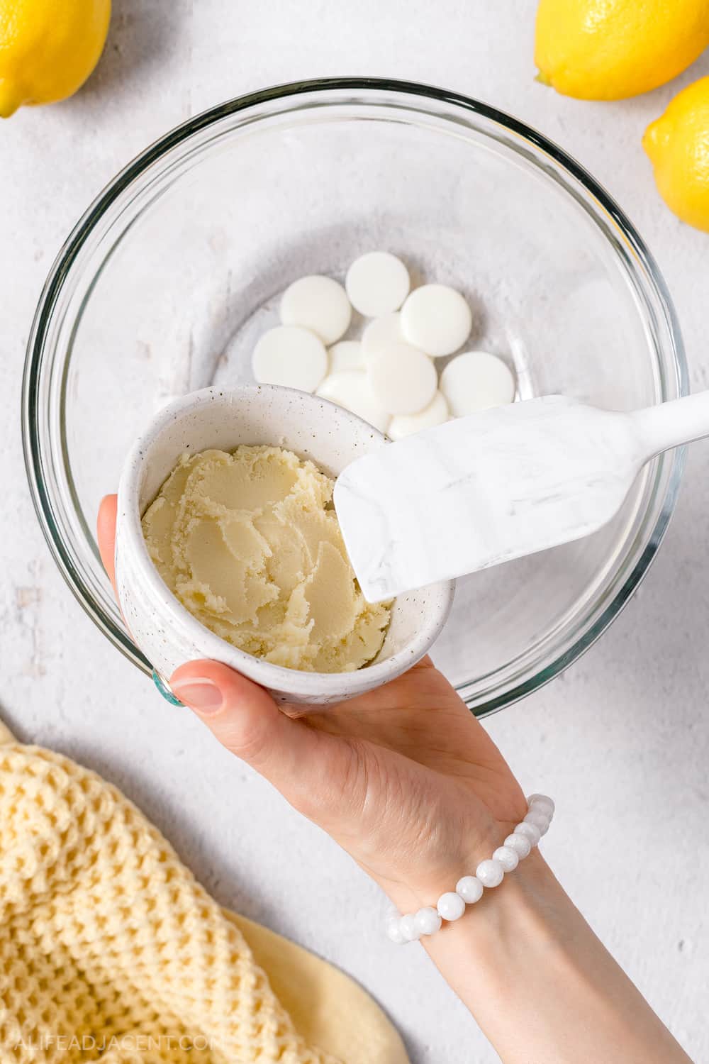 Adding shea butter to homemade body cream.