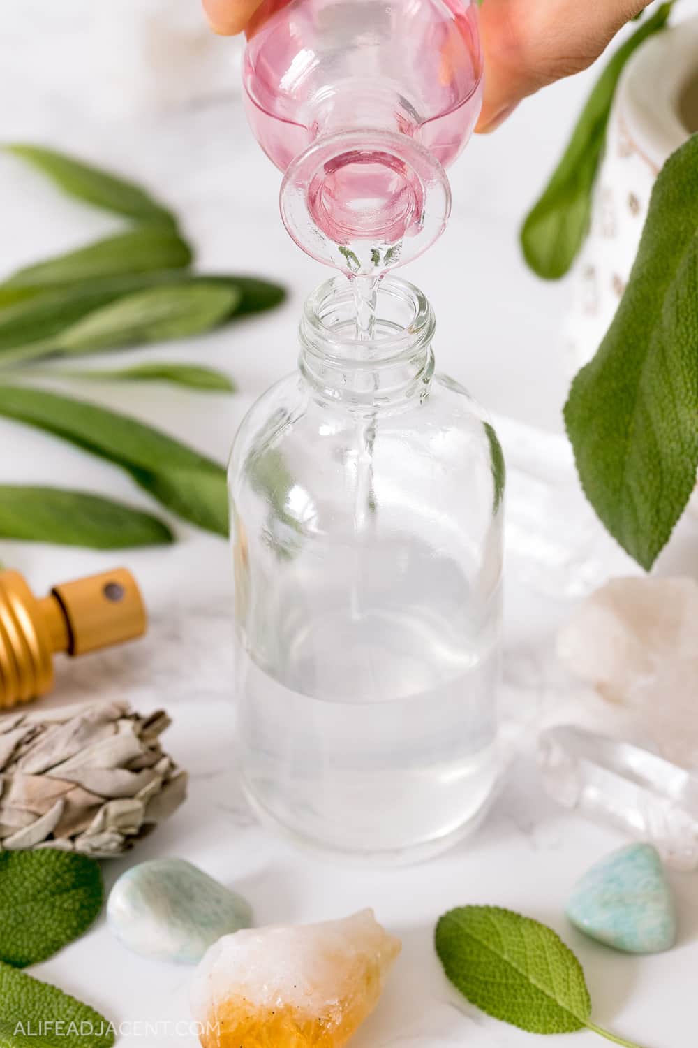 How to make smudge spray recipe – pouring sage essential oil into spray bottle.