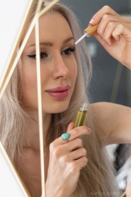 DIY lash serum being applied to long eyelashes by woman in mirror