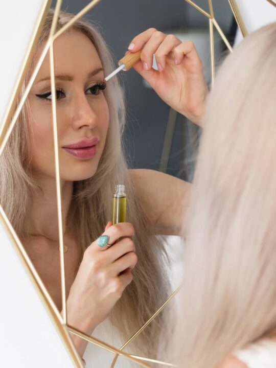 Woman applying DIY eyelash growth serum in mirror