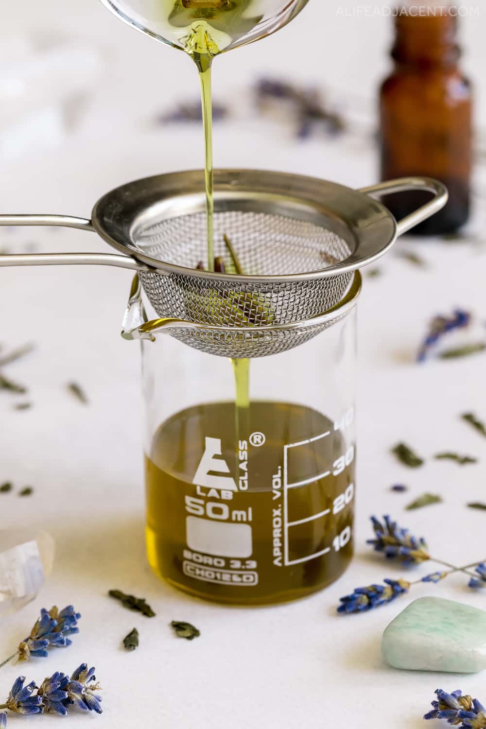 Straining herbal infused oil for eyebrow serum recipe.
