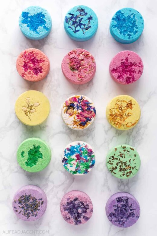 DIY shower steamers with flowers, herbs, botanicals, and Epsom salt decorations.
