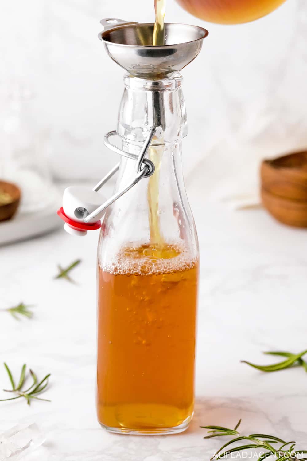 Pouring rosemary water for hair into glass bottle.