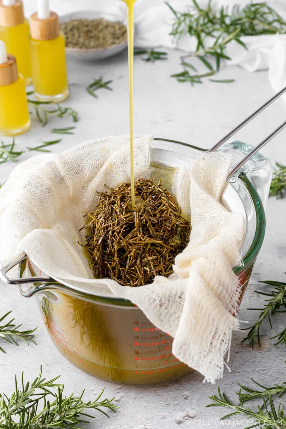 How to make rosemary oil for hair growth – straining rosemary leaves from infused oil.