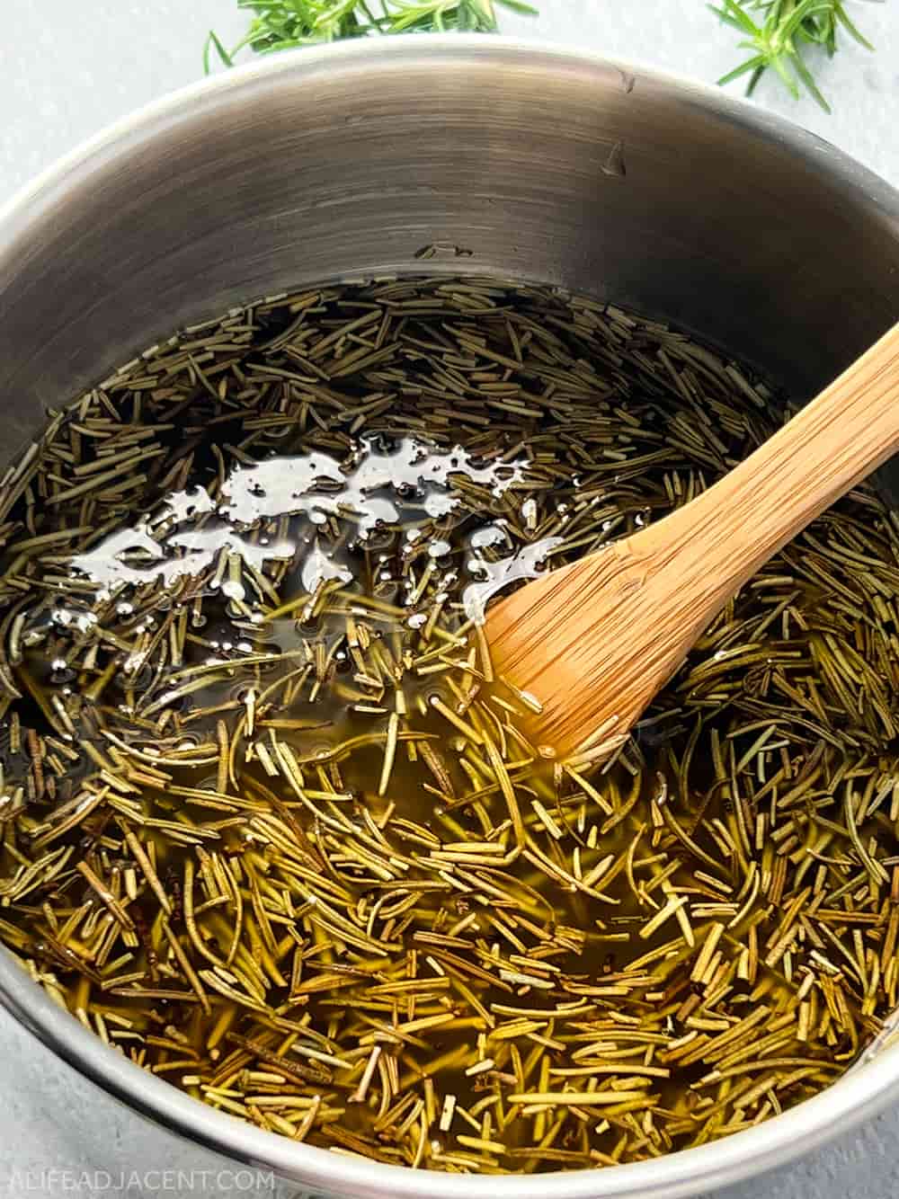 Rosemary infused oil cooking in pot.