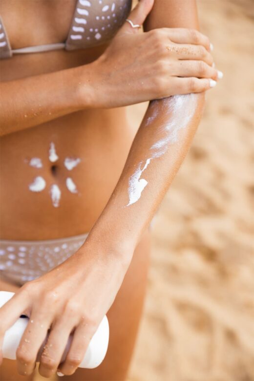 Woman applying non-toxic sunscreen to tanned skin