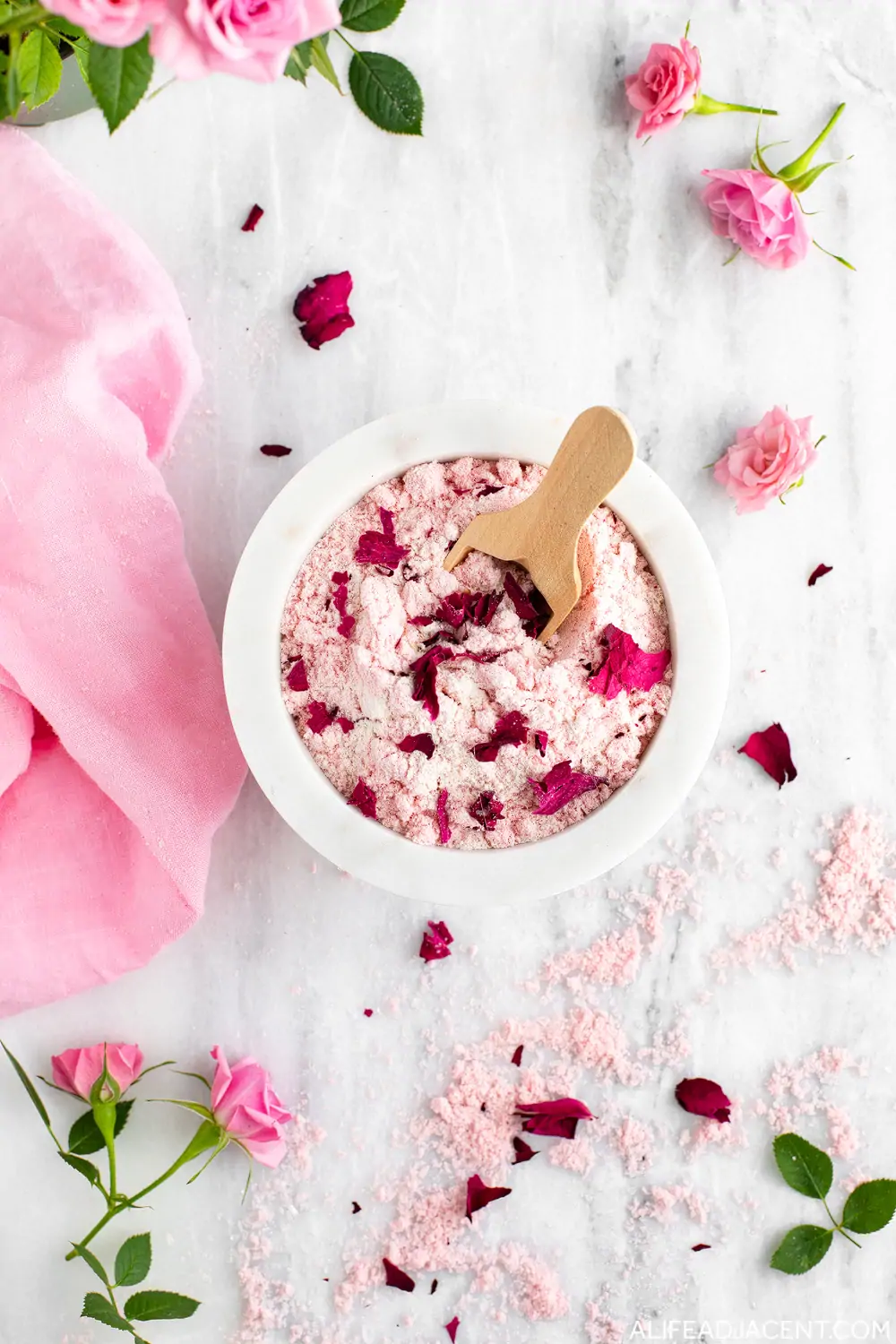 Homemade bath soak with pink rose petals