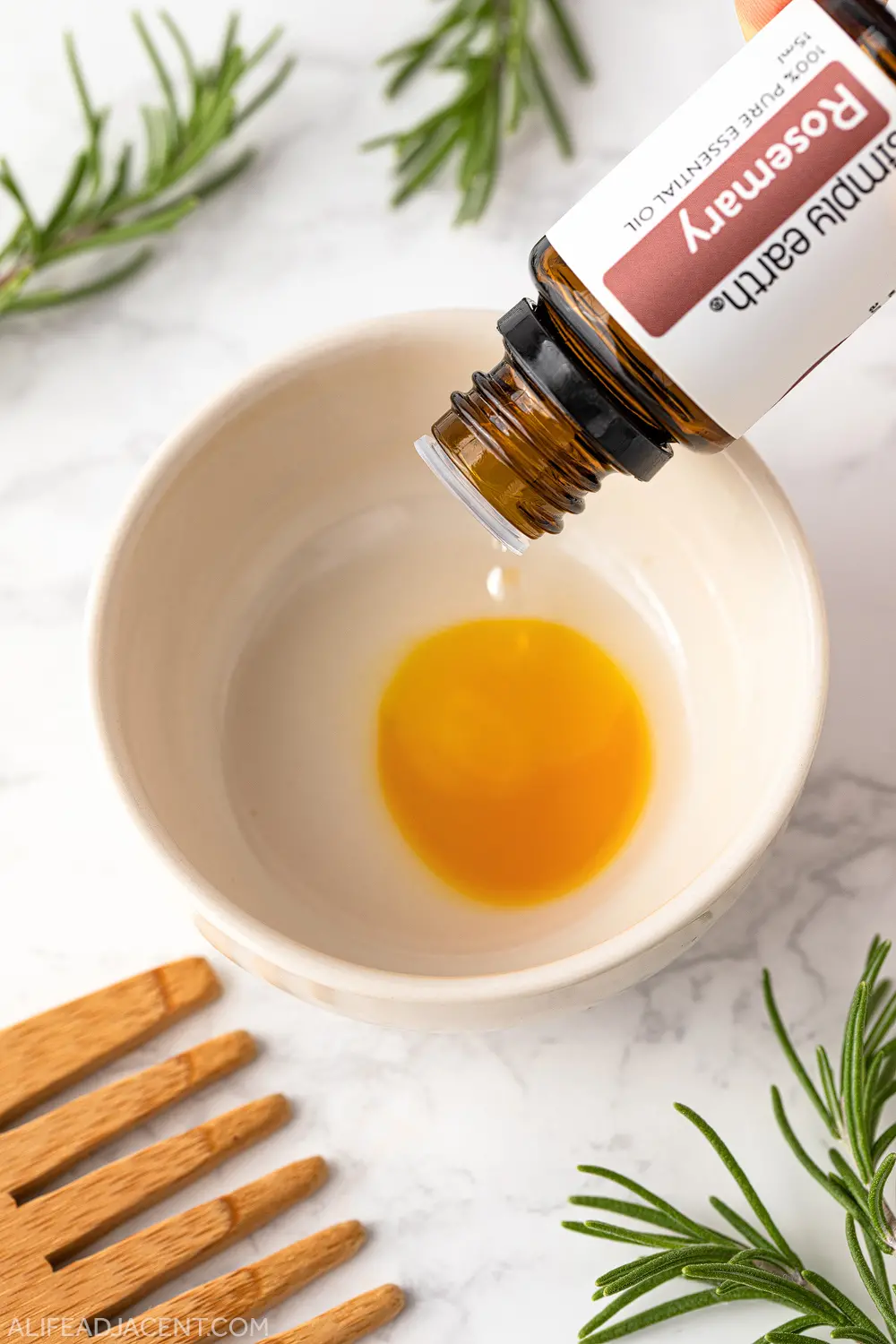Pouring rosemary essential oil into bowl for hair growth.