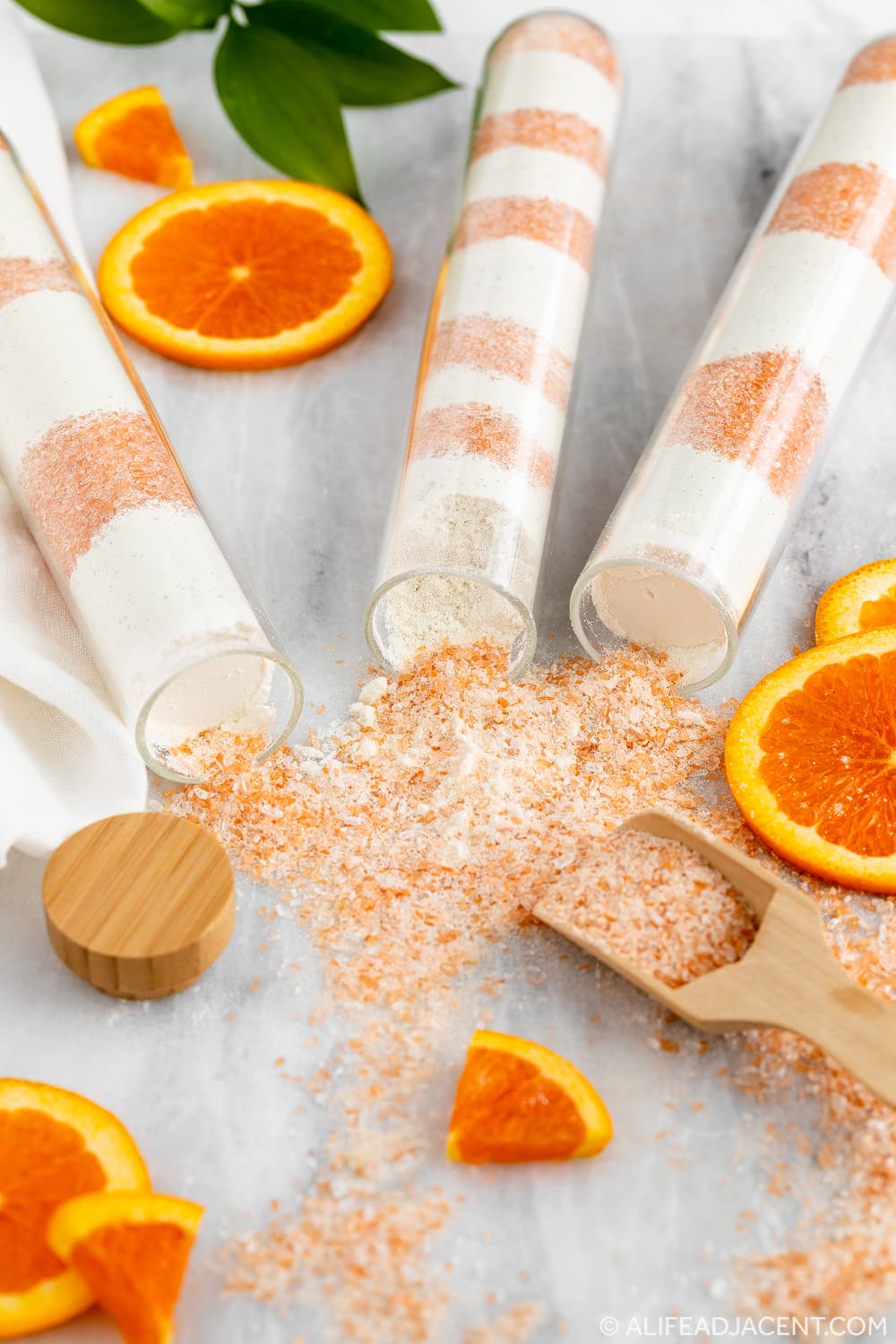 DIY orange creamsicle milk bath in bath tubes with salts spilling out and orange slices
