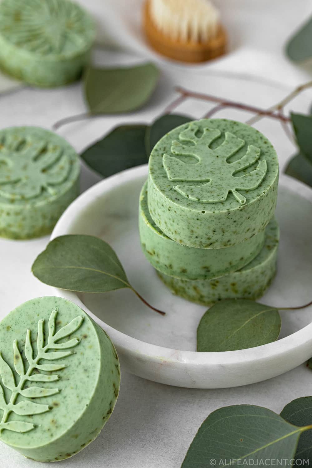 DIY eucalyptus soap bars on marble plate with eucalyptus leaves.
