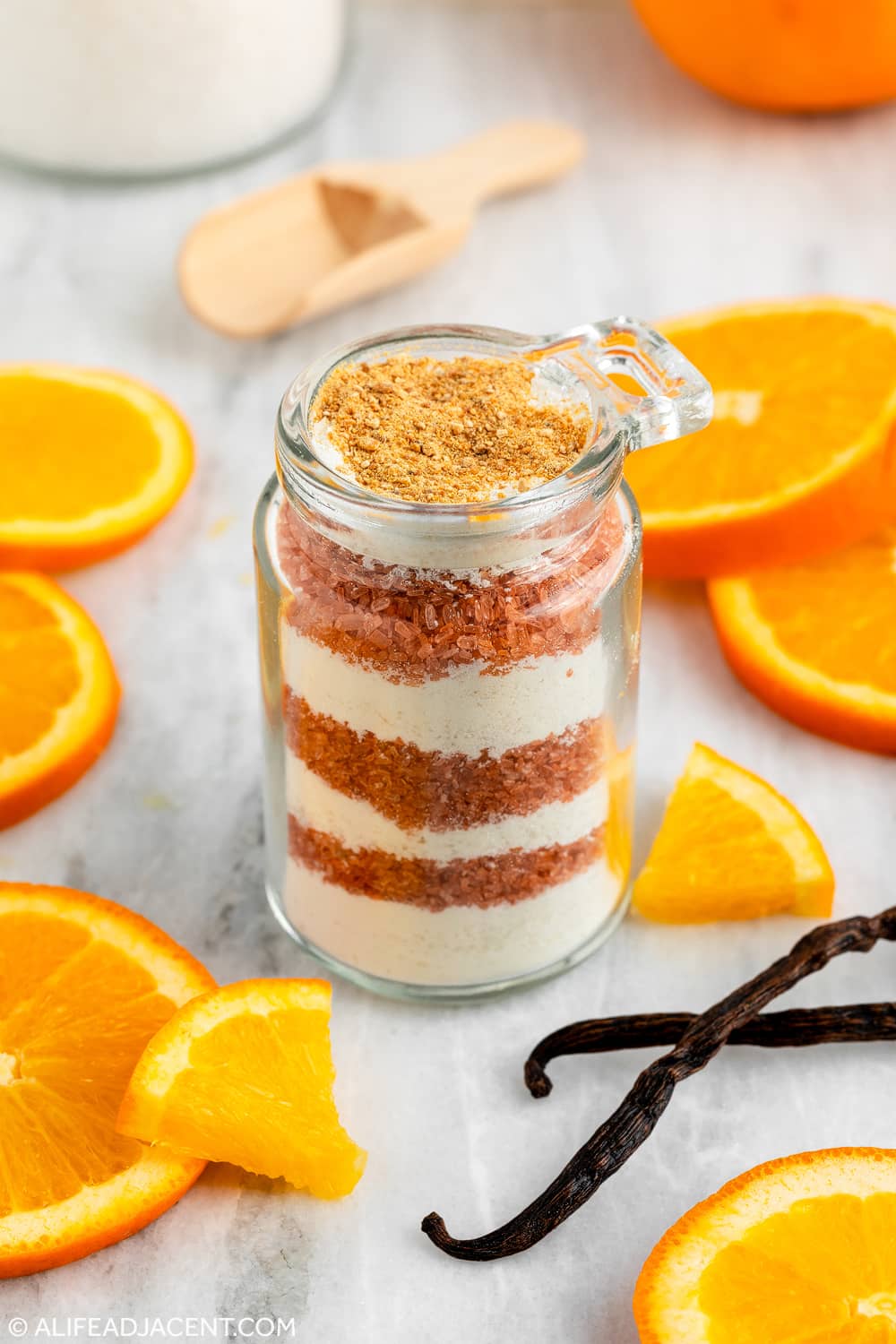 Creamsicle bath recipe layered in bath salt jar with vanilla beans and fresh orange slices