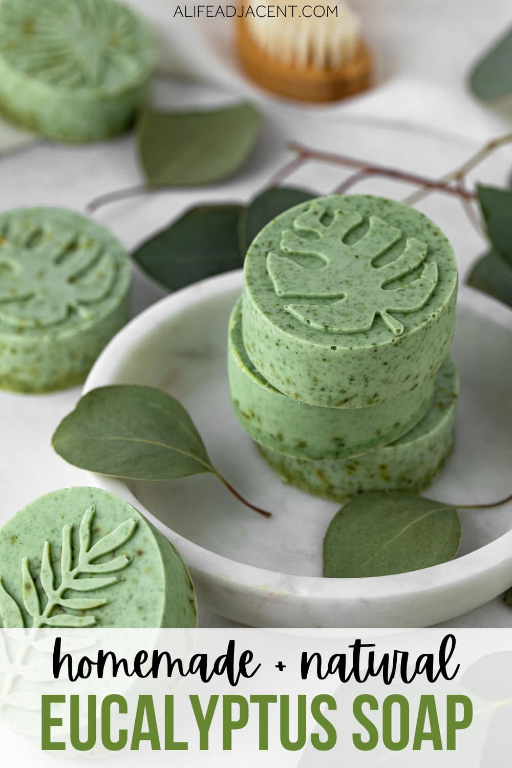 Green homemade eucalyptus soap bars with embossed leaf pattern on a white marble tray.