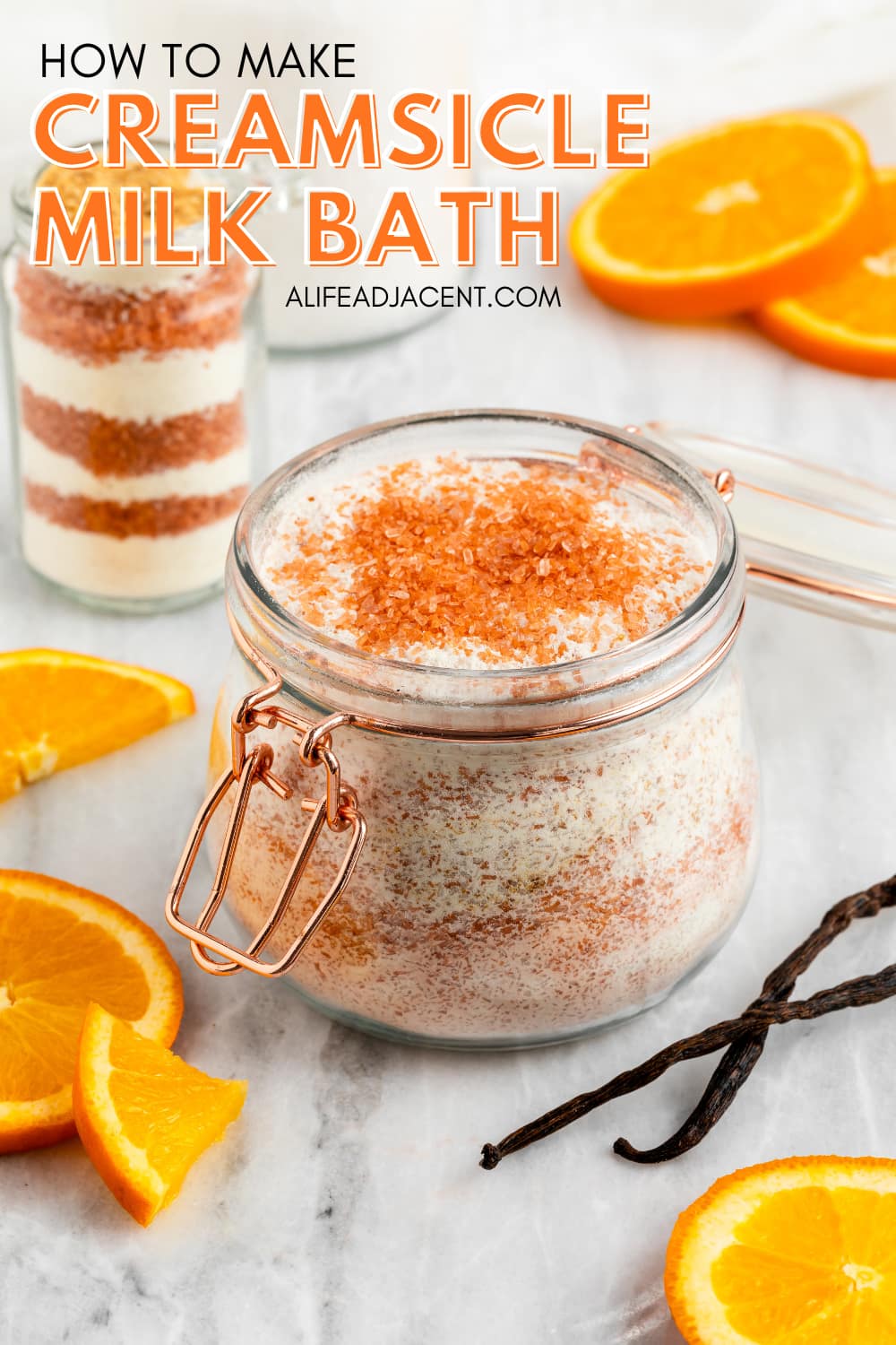 DIY orange creamsicle milk bath recipe made with milk powder, sweet orange, and vanilla, displayed in glass jars with orange slices and vanilla beans.