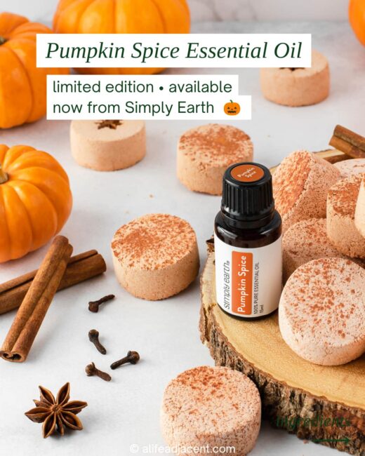 Pumpkin Spice essential oil bottle surrounded by pumpkins, cinnamon sticks, cloves and pumpkin spice shower bombs.
