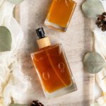 DIY body spray with essential oils in glass cologne bottles, featuring a woody fragrance for men.