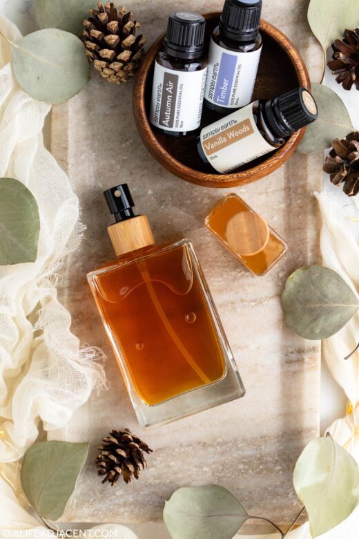 DIY essential oil body spray with a woodsy fragrance, surrounded by masculine essential oil blends and eucalyptus leaves.