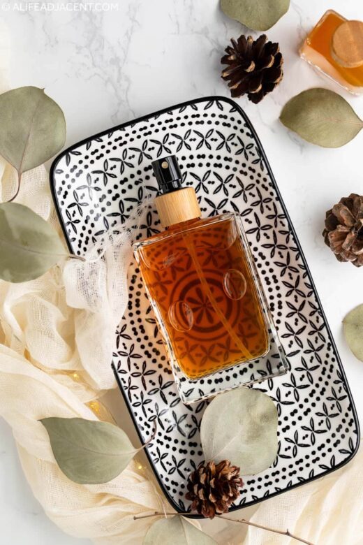 Natural men&rsquo;s body spray with essential oils in a glass perfume bottle, displayed on a black-and-white patterned decorative tray.