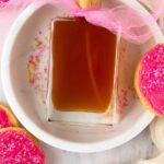 Sugar cookie perfume spray with pink sugar, frosted cookies, and a decorative pink tulle bow.