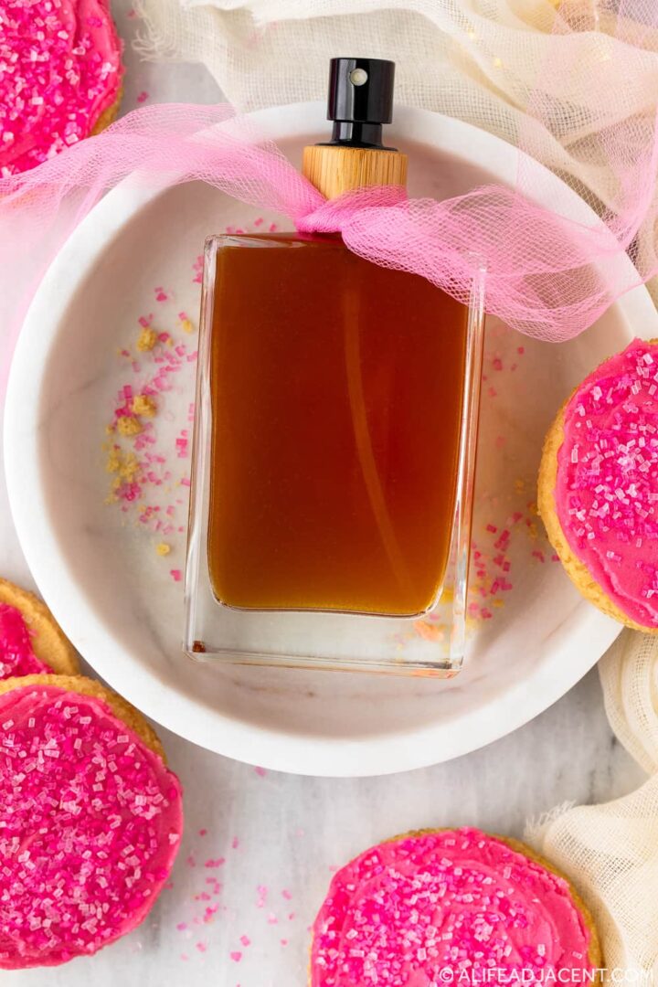 Sugar cookie perfume spray with pink sugar, frosted cookies, and a decorative pink tulle bow.